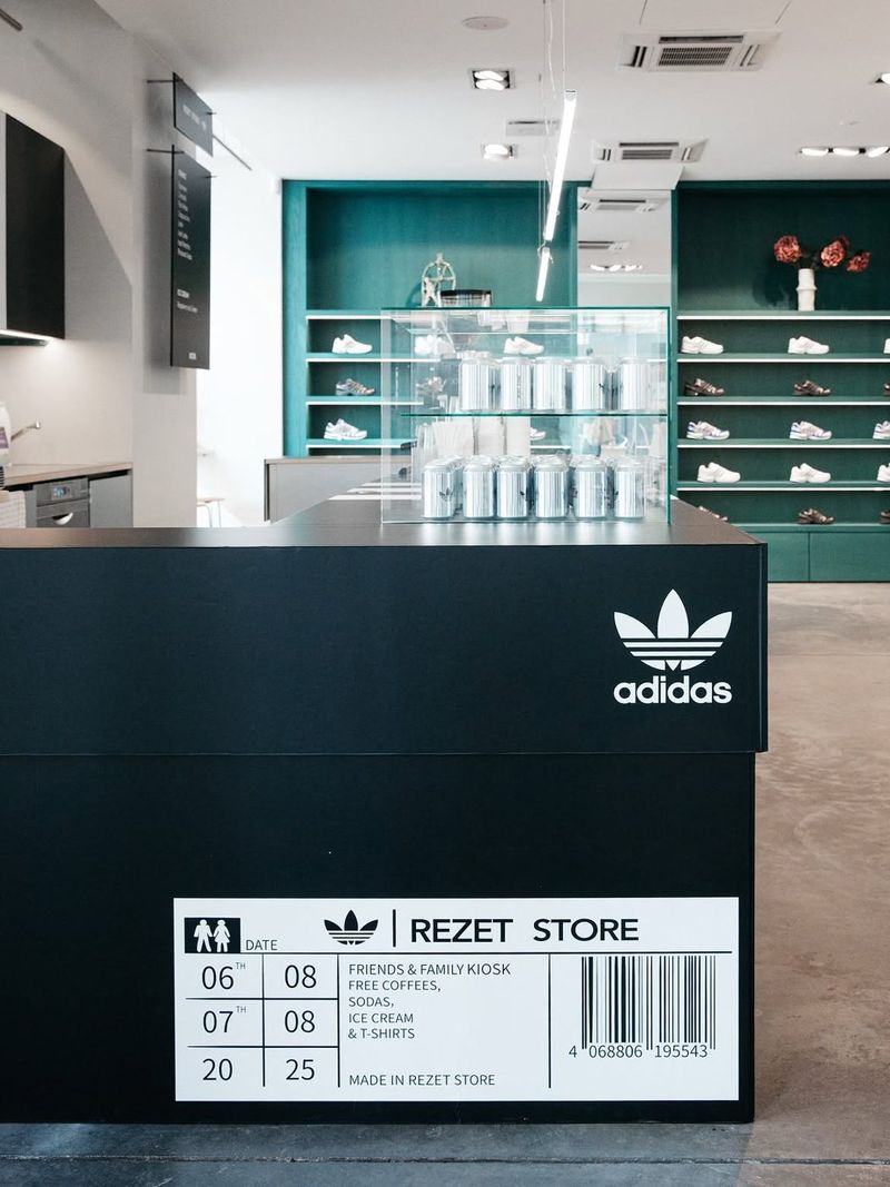 Close-up of the black kiosk counter with the adidas trefoil and a shoebox-style Rezet Store label.
